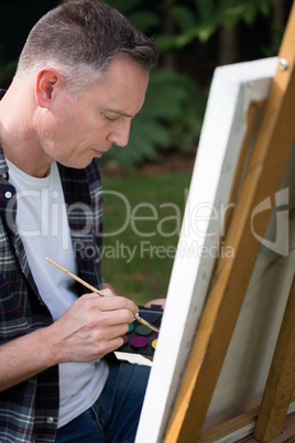 Man painting on canvas in garden