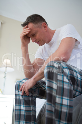 Worried man having a headache in bedroom