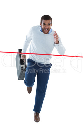 Male executive with briefcase running towards finish line