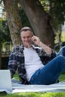 Man using laptop while talking on mobile phone