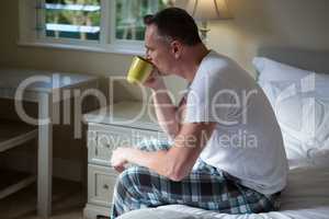 Man drinking cup of coffee in bedroom