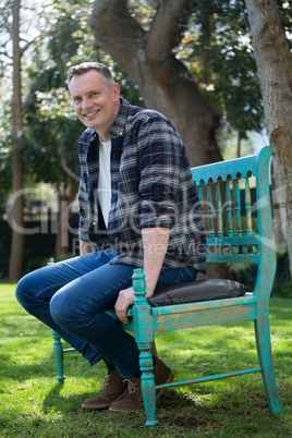 Smiling man sitting on bench in garden