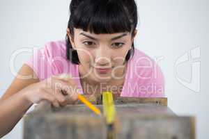 Woman measuring wooden plank with tape measure