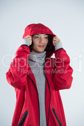 Woman in hooded jacket standing against white background