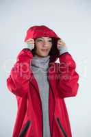 Woman in hooded jacket standing against white background