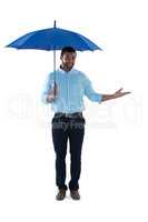 Male executive standing under umbrella