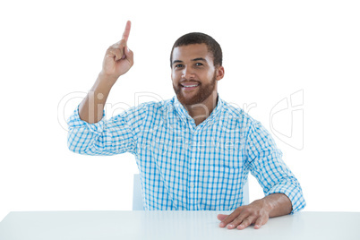 Male executive pointing upwards while sitting at desk