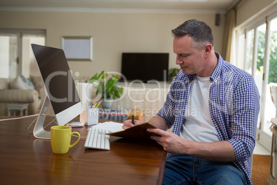 Man writing on diary in living room