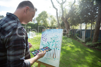 Man painting on canvas in garden