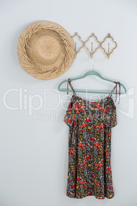 Hat and dress hanging against white wall