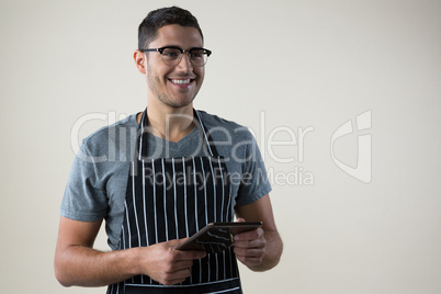 Smiling waiter standing with a digital tablet