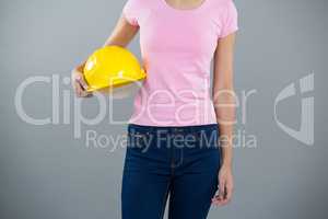 Woman holding hard hat against grey background