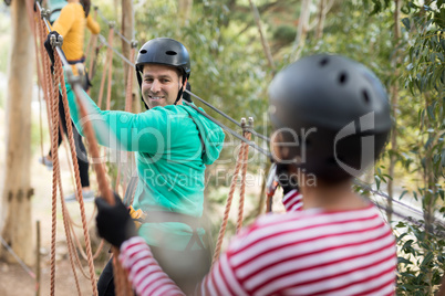 Friends enjoying zip line adventure in park