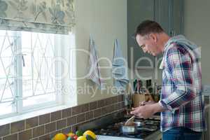 Man using digital tablet while preparing food in pan