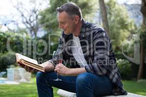 Man reading novel while having glass of red wine