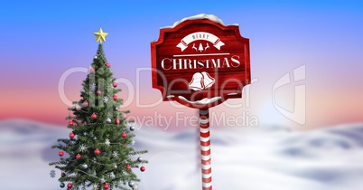 Merry Christmas text on Wooden signpost in Christmas Winter landscape with Christmas tree