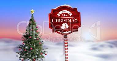 Merry Christmas text on Wooden signpost in Christmas Winter landscape with Christmas tree