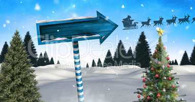 Wooden signpost in Christmas Winter landscape with Christmas tree and Santa's sleigh and reindeers