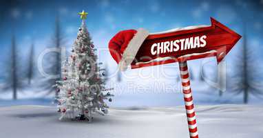 Christmas text on Wooden signpost in Christmas Winter landscape and Santa hat with Christmas tree