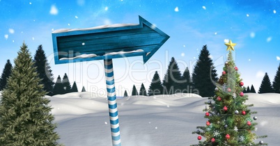 Wooden signpost in Christmas Winter landscape with Christmas tree