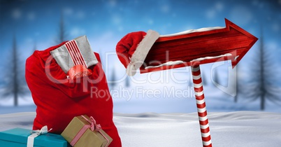 Santa's bag with gifts and Wooden signpost in Christmas Winter landscape and Santa hat