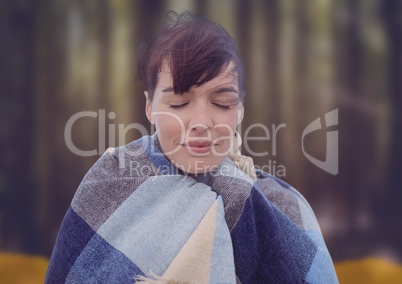 Woman's face in forest with leaves with blanket