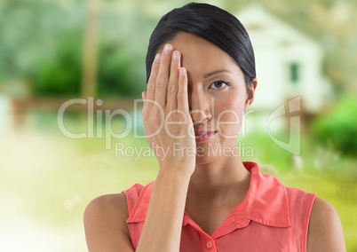 Woman holding hand over her eye in countryside