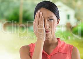 Woman holding hand over her eye in countryside