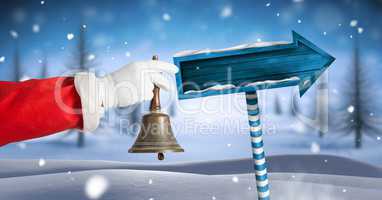 Santa ringing bell and Wooden signpost in Christmas Winter landscape