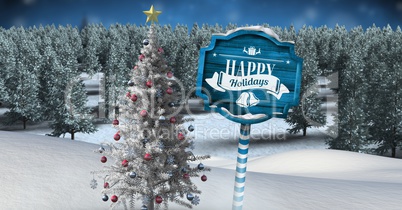 Happy holidays text on Wooden signpost in Christmas Winter landscape with Christmas tree