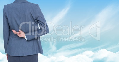 Businesswoman with fingers crossed in sky