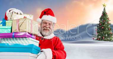 Santa holding gifts in Christmas Winter landscape with Christmas tree