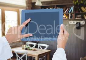 Hand holding tablet with cafe background