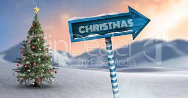 Christmas text on Wooden signpost in Christmas Winter landscape with Christmas tree