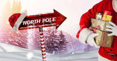 North Pole text and Santa holding gifts with Wooden signpost in Christmas Winter landscape and Santa
