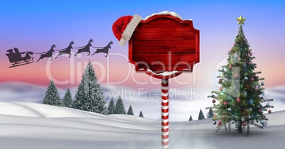 Wooden signpost in Christmas Winter landscape with Christmas tree and Santa's sleigh and reindeer's