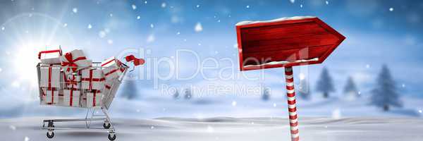 Shopping trolley with gifts and wooden sign in Christmas Winter landscape