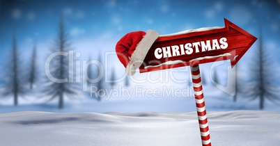 Christmas text on Wooden signpost in Christmas Winter landscape and Santa hat