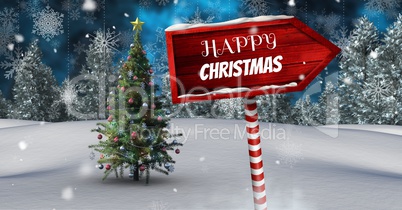 Happy Christmas text on Wooden signpost in Christmas Winter landscape with Christmas tree