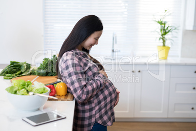 Smiling pregnant woman touching her stomach