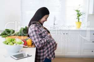 Smiling pregnant woman touching her stomach