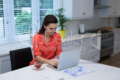 Woman using laptop in kitchen