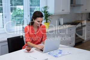 Woman using laptop in kitchen