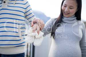 Pregnant woman and her husband holding baby socks in balcony