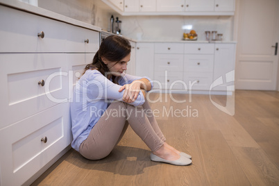 Worried woman sitting in kitchen