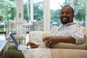 Man using laptop on sofa in living room