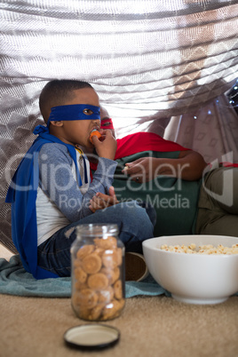 Father and son in superhero costume having popcorn