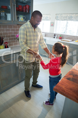 Father and daughter dancing together in kitchen