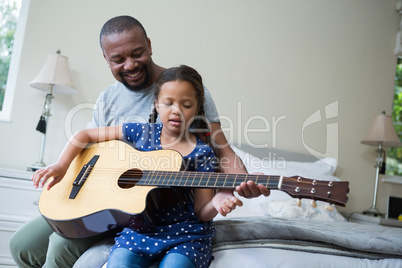 Father teaching his daughter to play the guitar