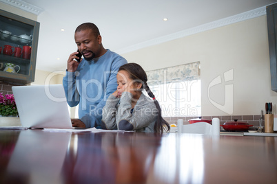 Father talking on mobile phone and daughter watching